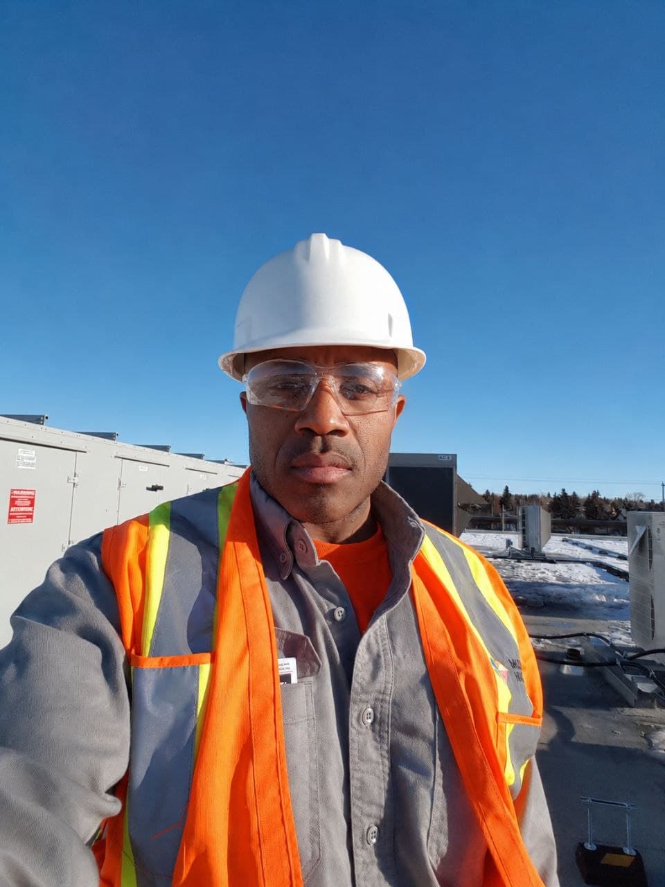 Verified contractor in hard hat and safety vest on a commercial rooftop HVAC job site